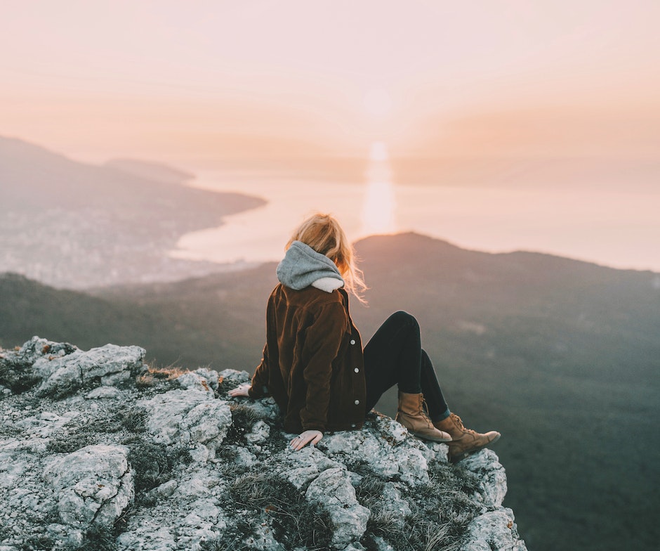 Frau beim Genießen des Sonnenuntergangs auf einer Klippe