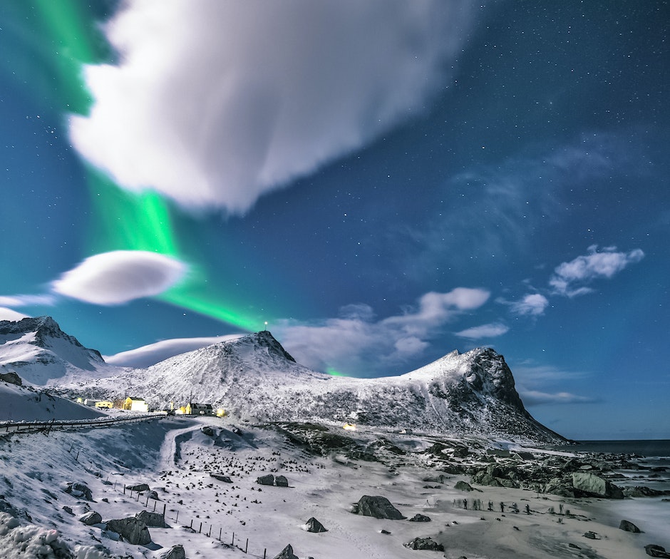 Schneebedeckte Berge bei Tag mit Polarlichtern am blauen Himmel