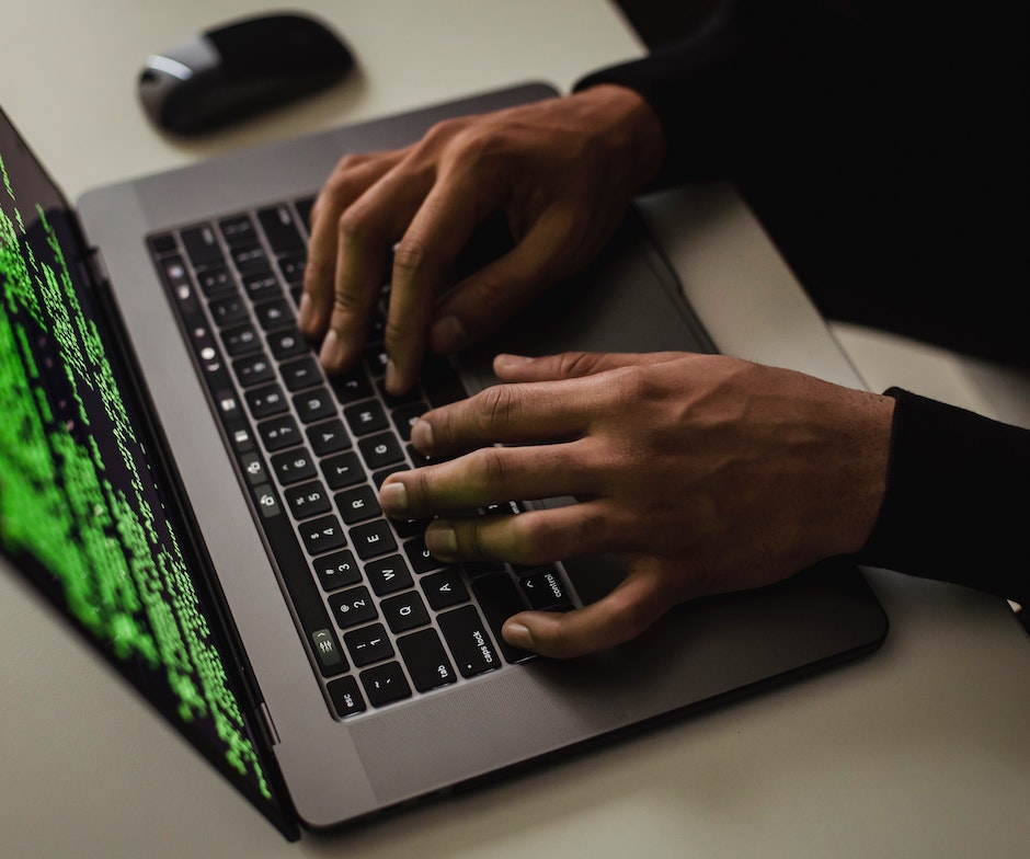 una persona escribiendo en el teclado del portátil y el ratón a un lado