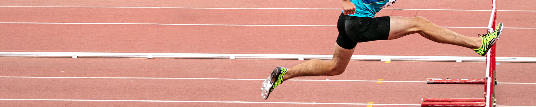 runner jumping over hurdle