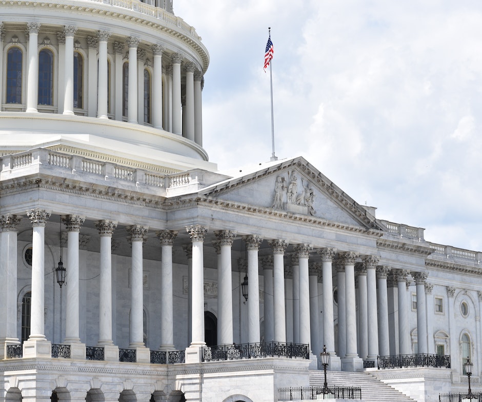 government building with pillars and American flag on top of the building waving