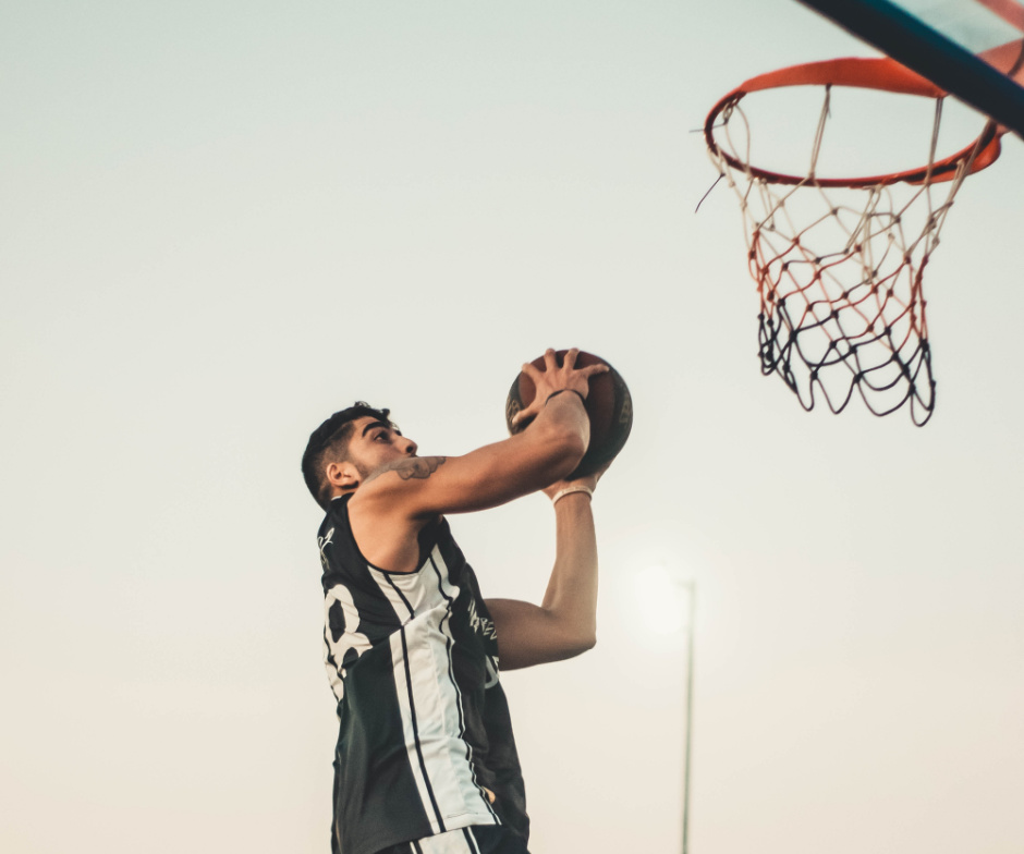 person shooting basketball in net while jumping