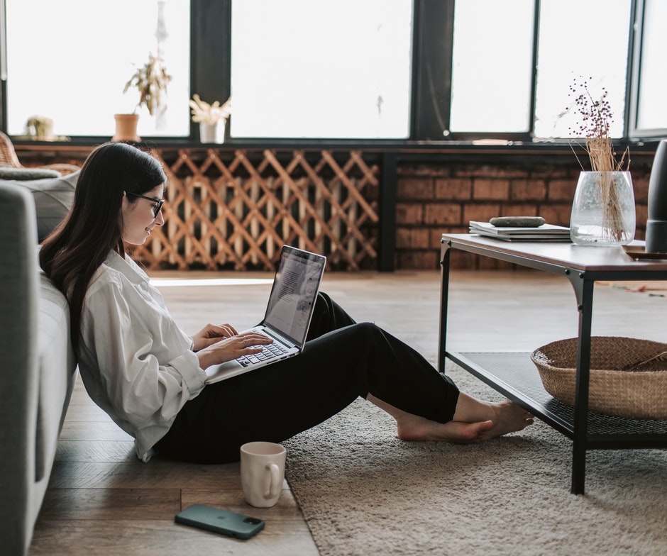 Woman sitting on the floor typing on laptop 