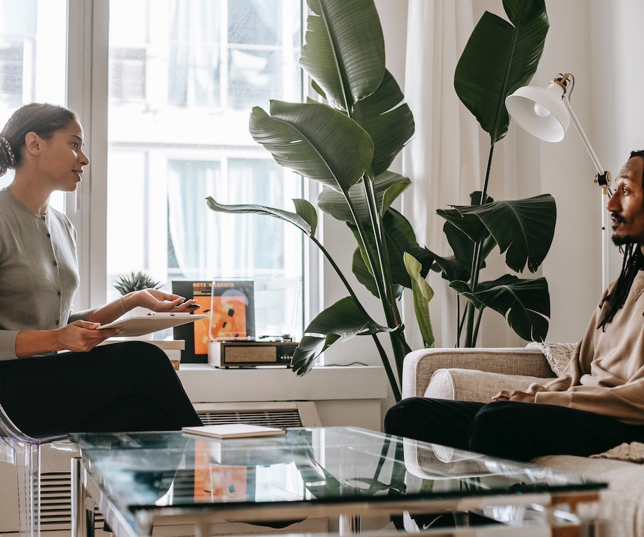 A Woman sitting on a sofa and talking to a person in her apartment