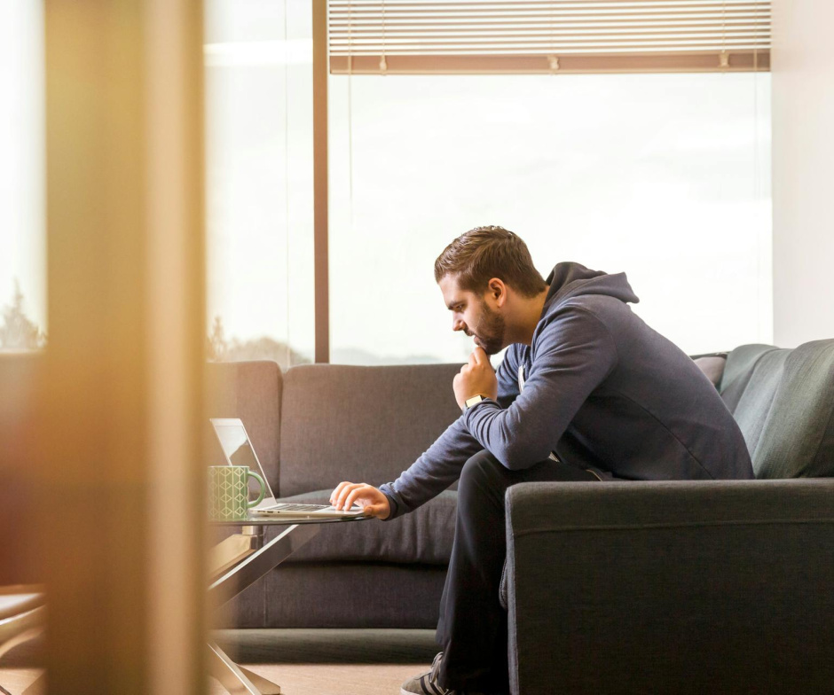 person sitting on sofa and working on laptop