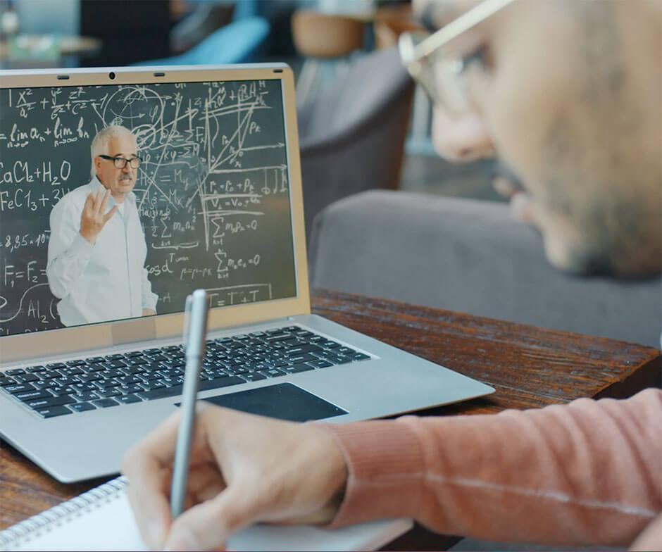 person taking notes looking at laptop showing a blackboard