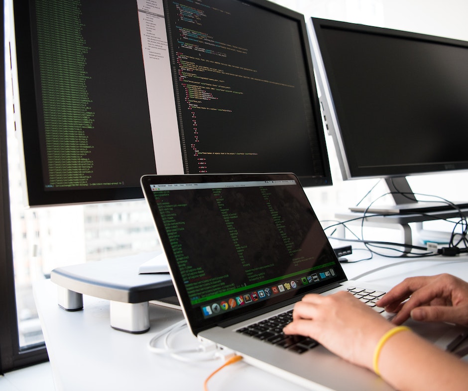 person typing on laptop with external monitors connected to it