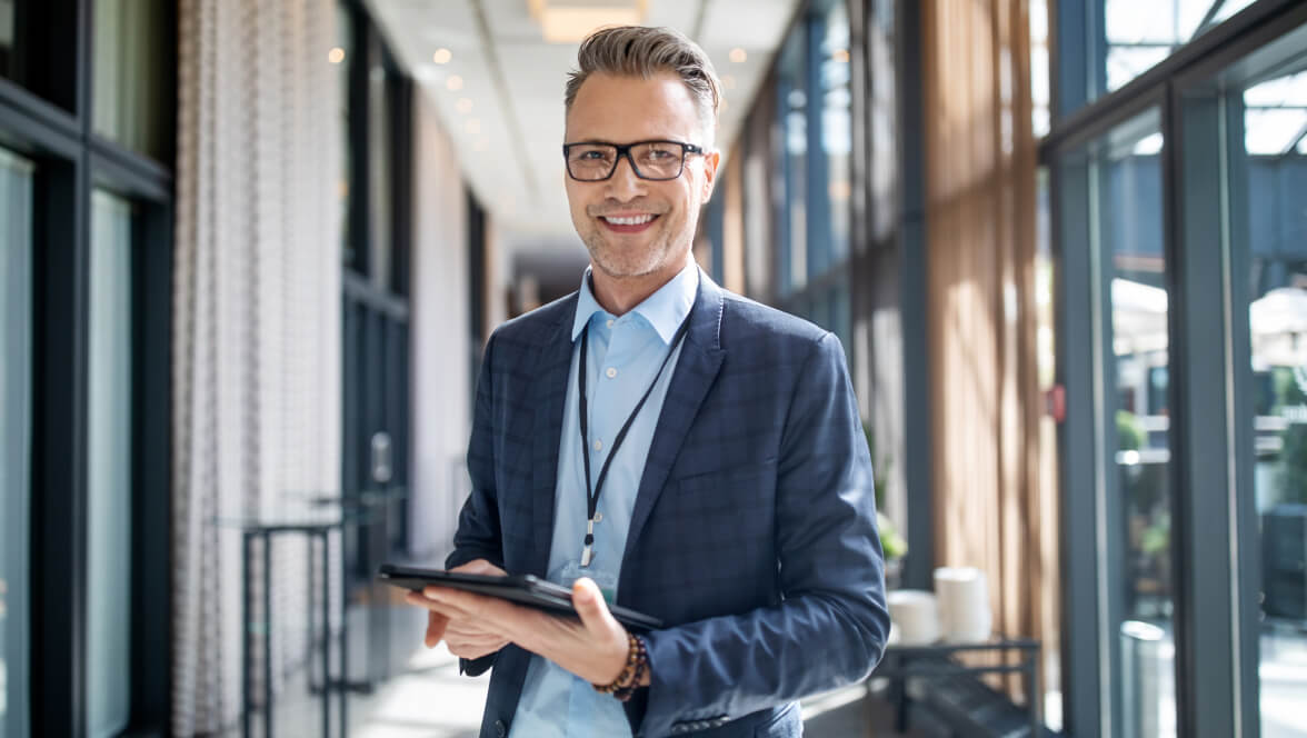 Person wearing professional suit with glasses holding tablet and smiling